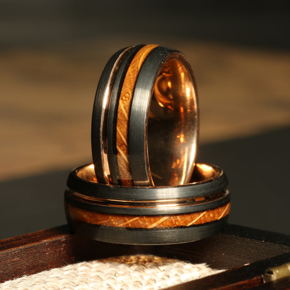 Men’s black tungsten whiskey barrel wedding band with rose gold interior
